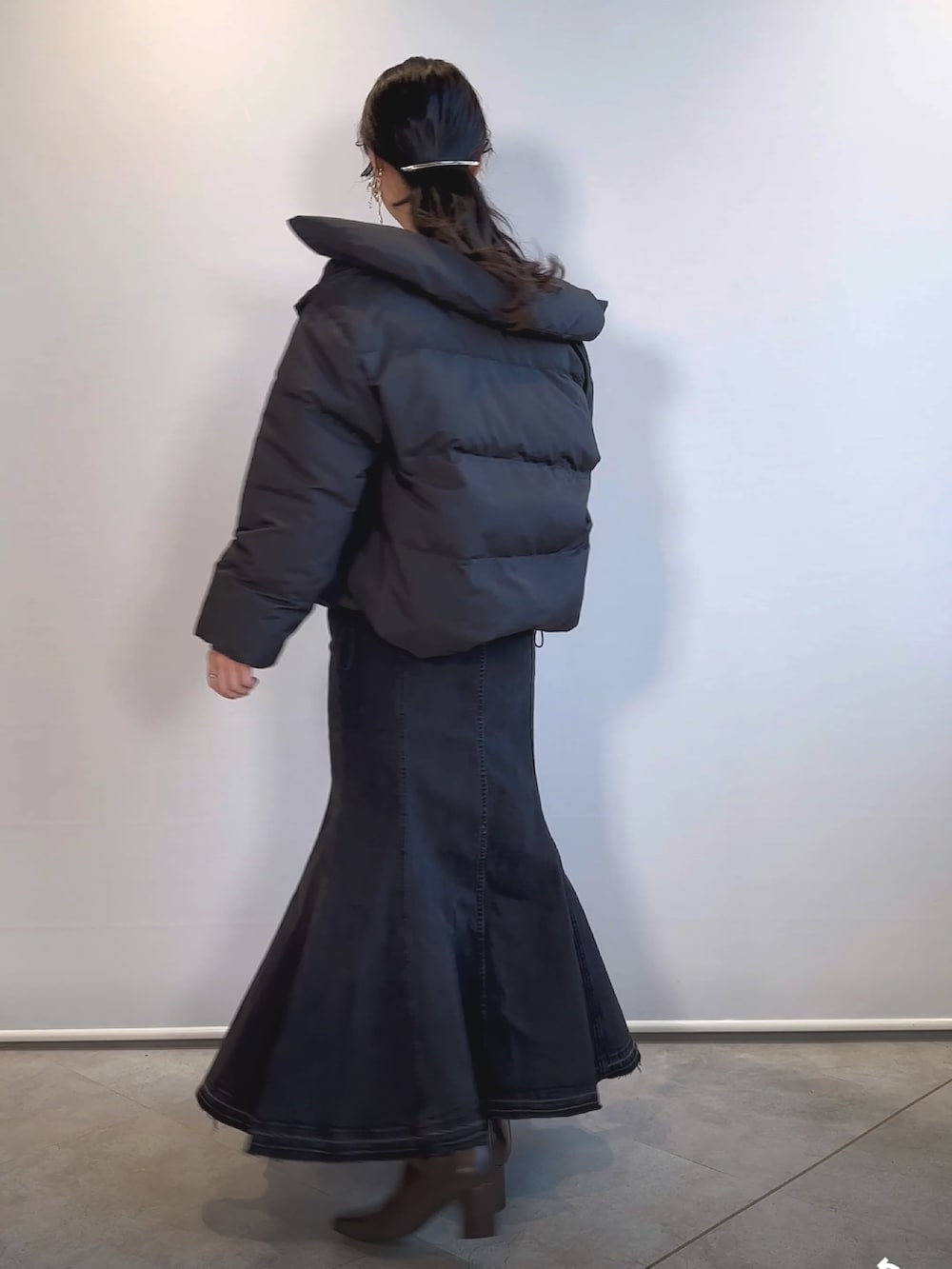 ブラウン系のブーツ、ブラック系のデニムスカート、ブラック系のダウンジャケット/コートを着用したレディースの冬コーディネートの3枚目の写真