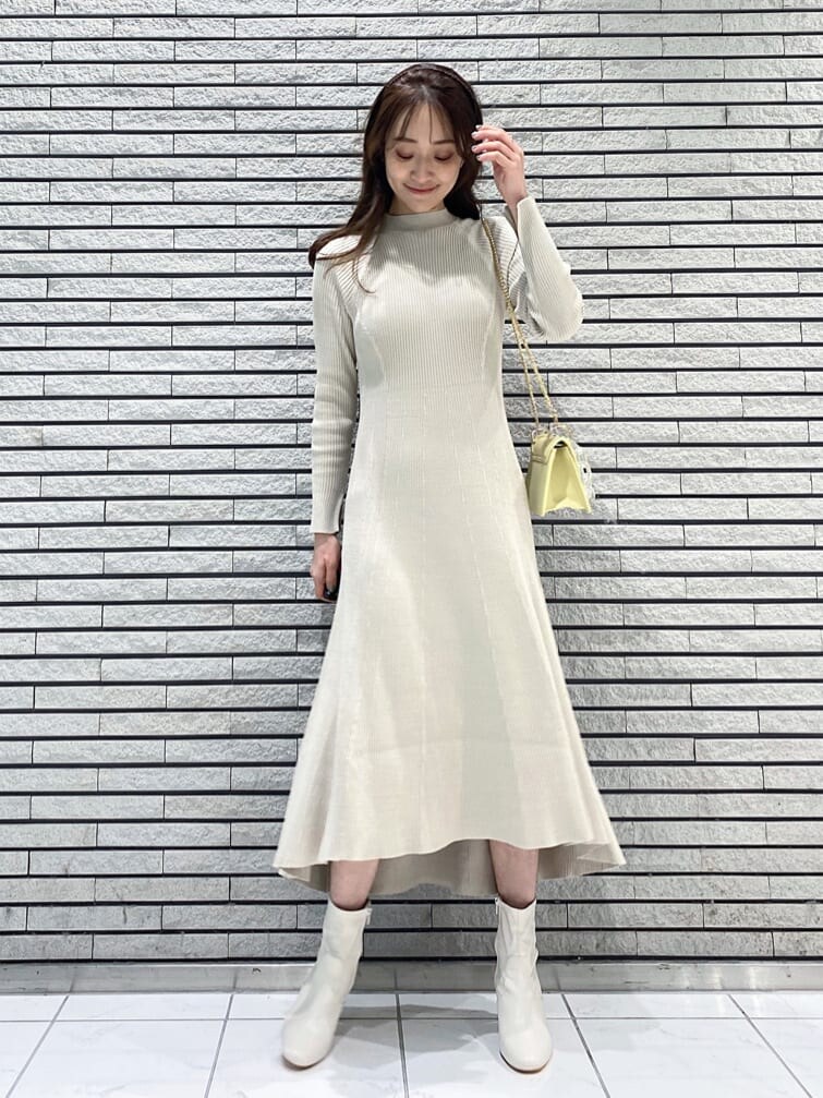 イエロー系のショルダーバッグ、ベージュ系のワンピース、ホワイト系のその他シューズを着用したレディースの冬コーディネートの6枚目の写真