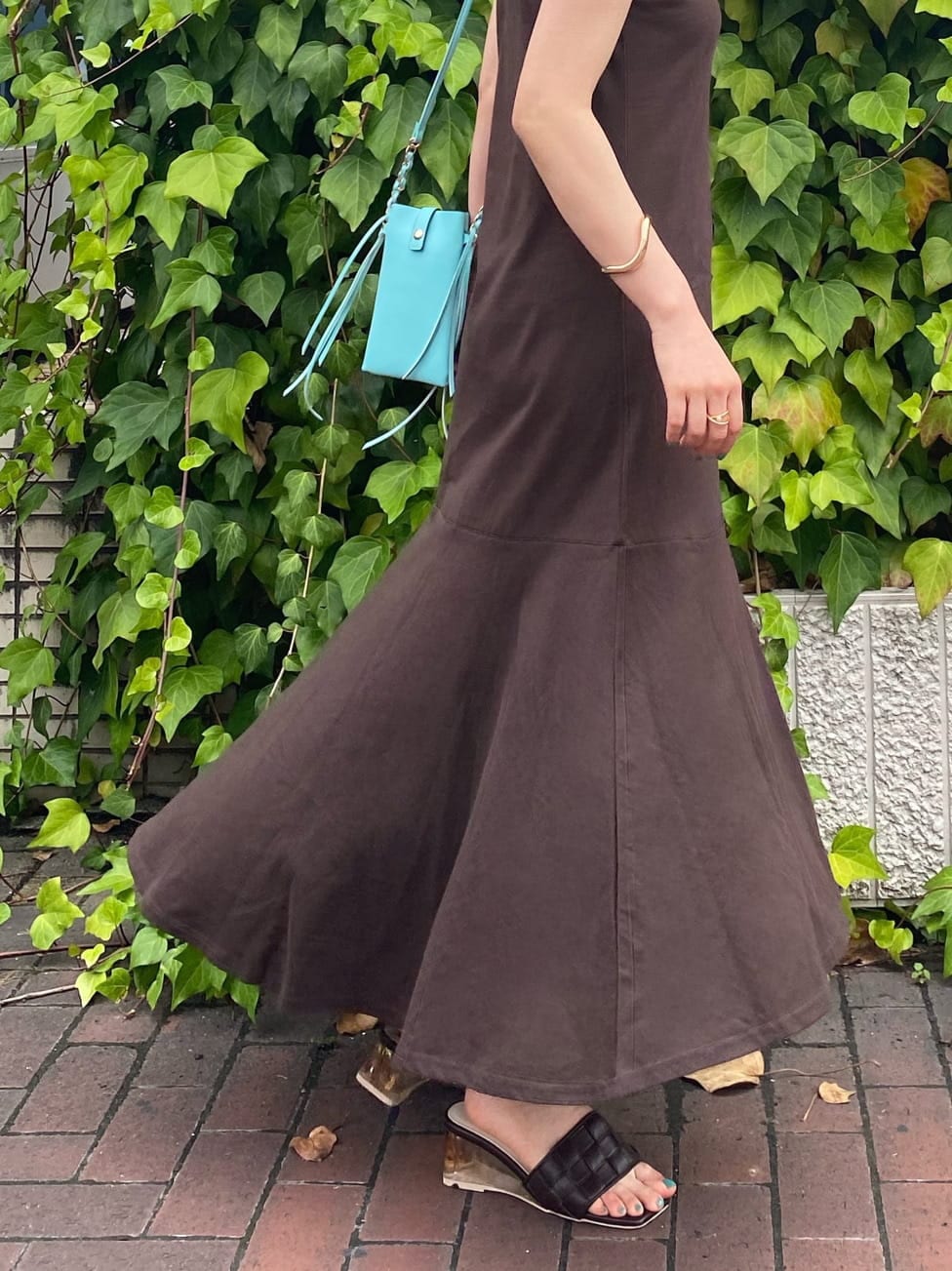 グリーン系のショルダーバッグ、ブラウン系のサンダル、ベージュ系のキャミソールを着用したレディースの夏コーディネートの8枚目の写真