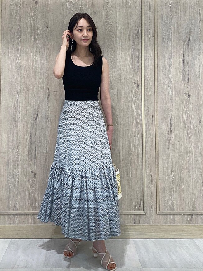 ホワイト系のハンドバッグ、ブルー系のスカート、ブラック系のニット/セーターを着用したレディースの夏コーディネートの2枚目の写真