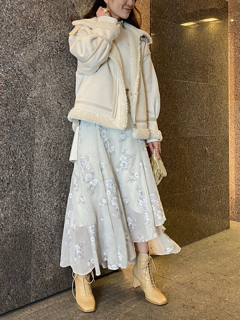 ベージュ系のクラッチバッグ、ホワイト系のムートンコート、ホワイト系のニット/セーターを着用したレディースの秋コーディネートの2枚目の写真