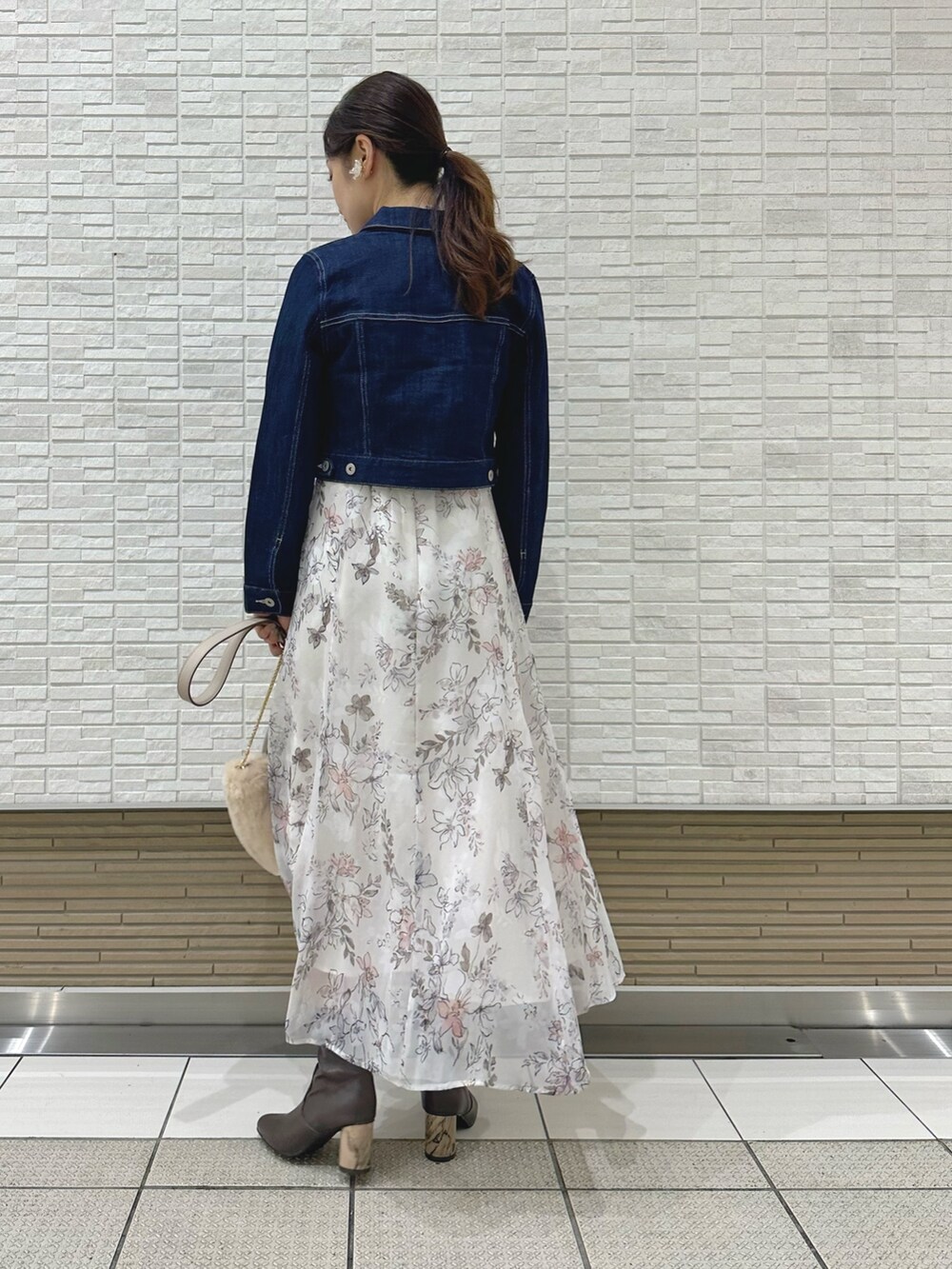 ブラウン系のブーツ、ホワイト系のハンドバッグ、ブルー系のデニムジャケットを着用したレディースの夏コーディネートの4枚目の写真