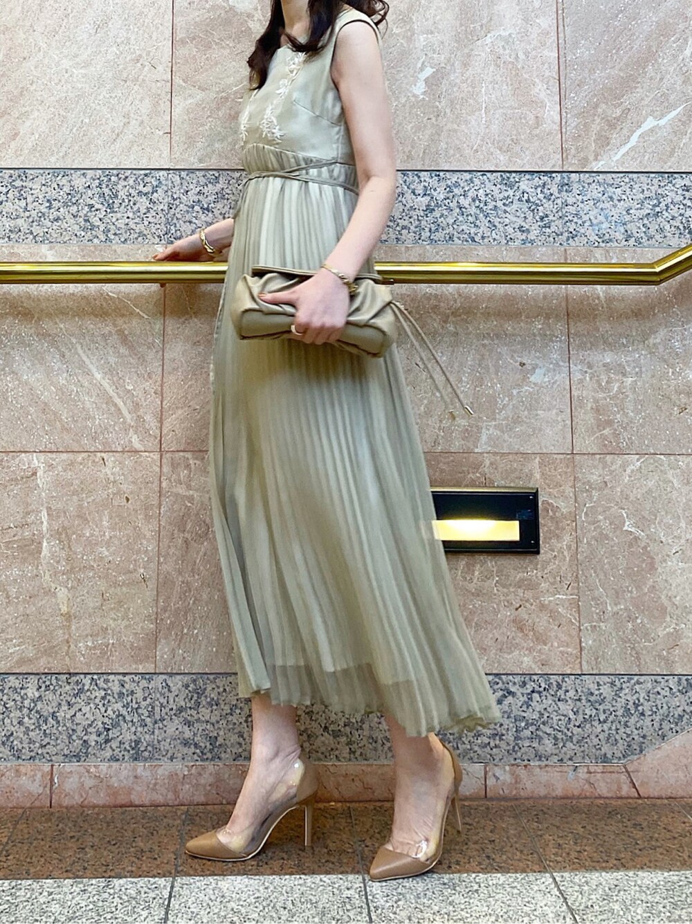 グリーン系のワンピース、ベージュ系のパンプス、ベージュ系のクラッチバッグを着用したレディースの春コーディネートの3枚目の写真