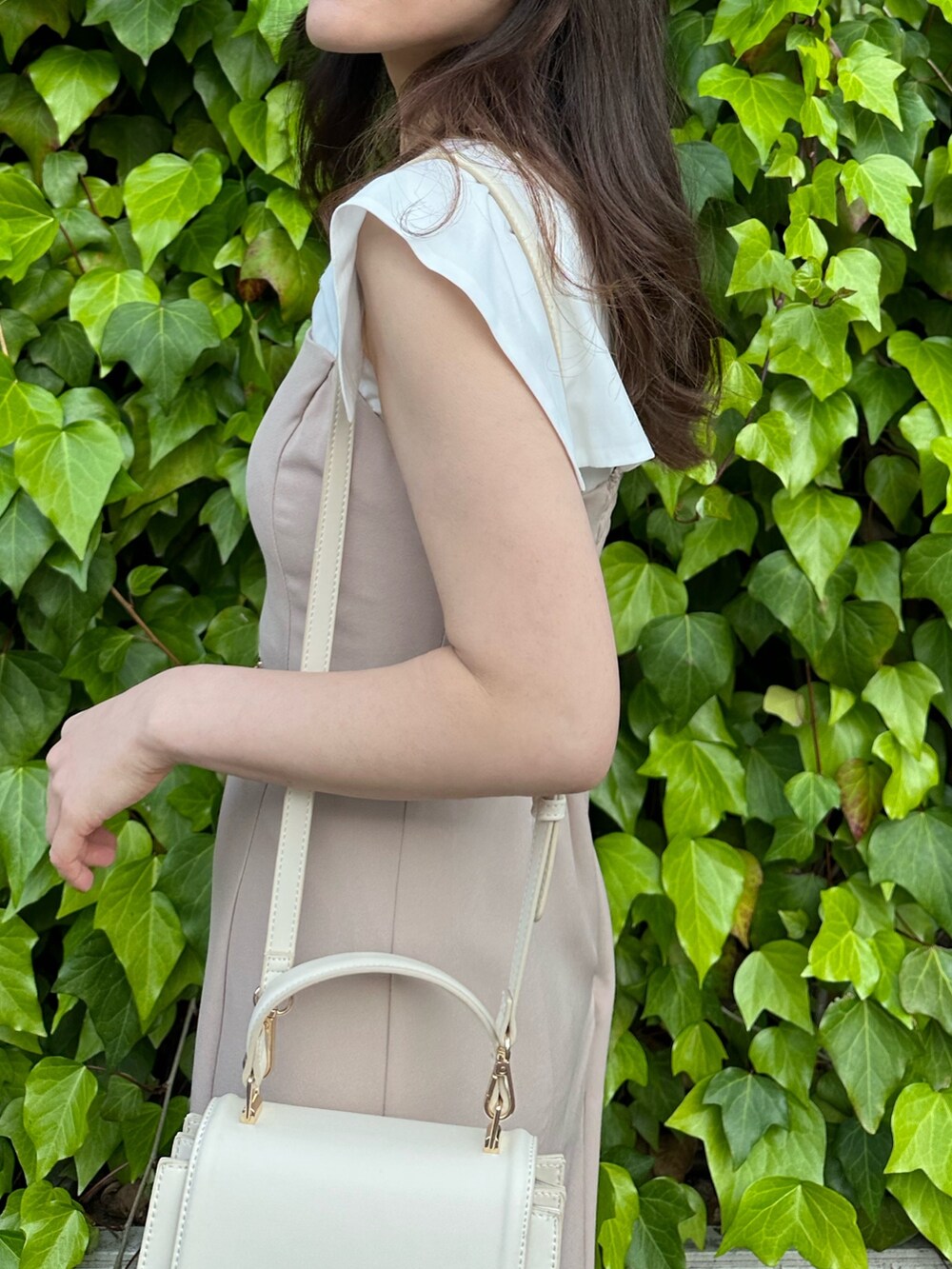 その他のサンダル、ホワイト系のハンドバッグ、ベージュ系のワンピースを着用したレディースの春コーディネートの5枚目の写真