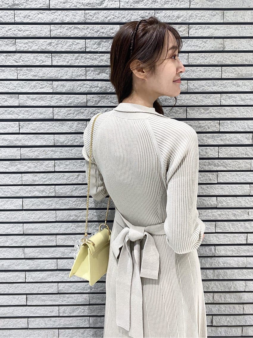 イエロー系のショルダーバッグ、ベージュ系のワンピース、ホワイト系のその他シューズを着用したレディースの冬コーディネートの4枚目の写真