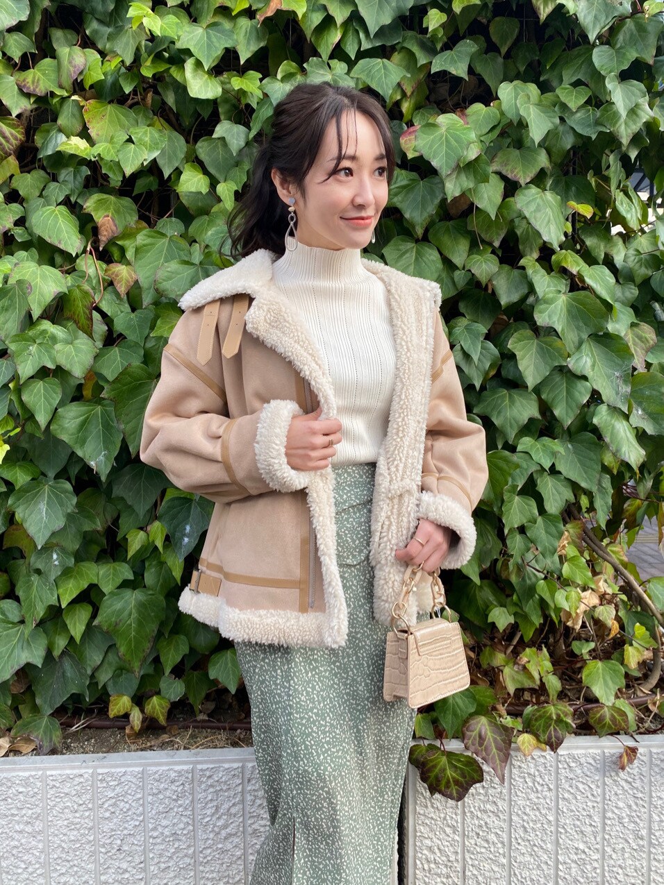 ベージュ系のムートンコート、ホワイト系のニット/セーター、ベージュ系のスカートを着用したレディースの冬コーディネートの3枚目の写真