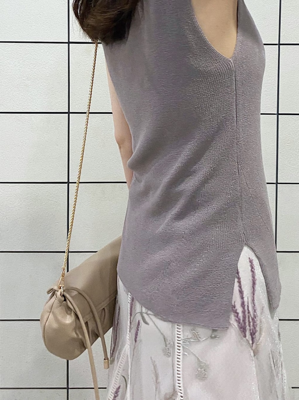 ベージュ系のクラッチバッグ、ブラウン系のサンダル、ホワイト系のスカートを着用したレディースの夏コーディネートの5枚目の写真