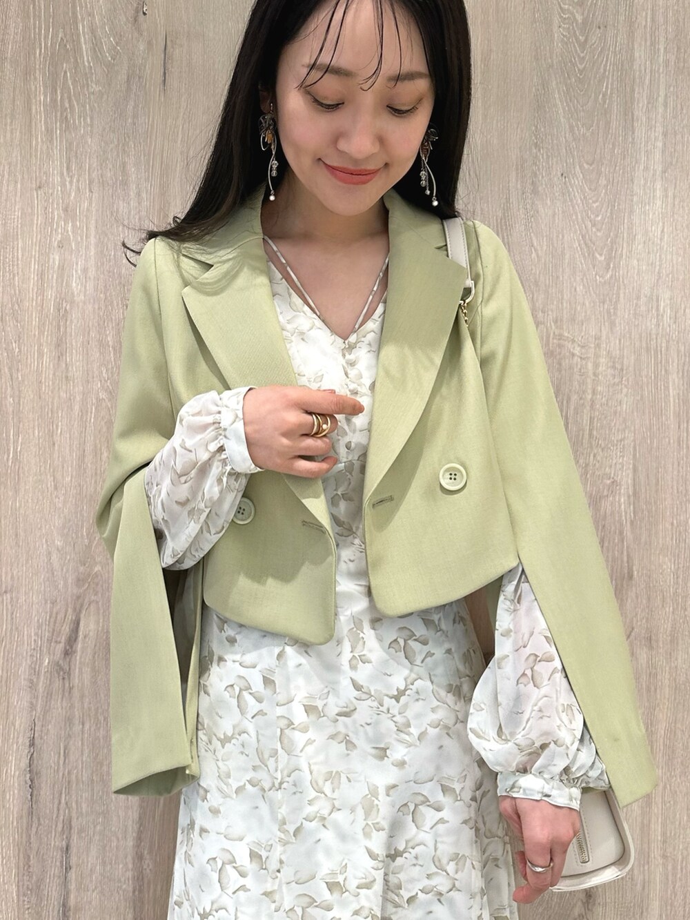 ホワイト系のハンドバッグ、ブラウン系のブーツ、グリーン系のテーラードジャケットを着用したレディースの冬コーディネートの6枚目の写真