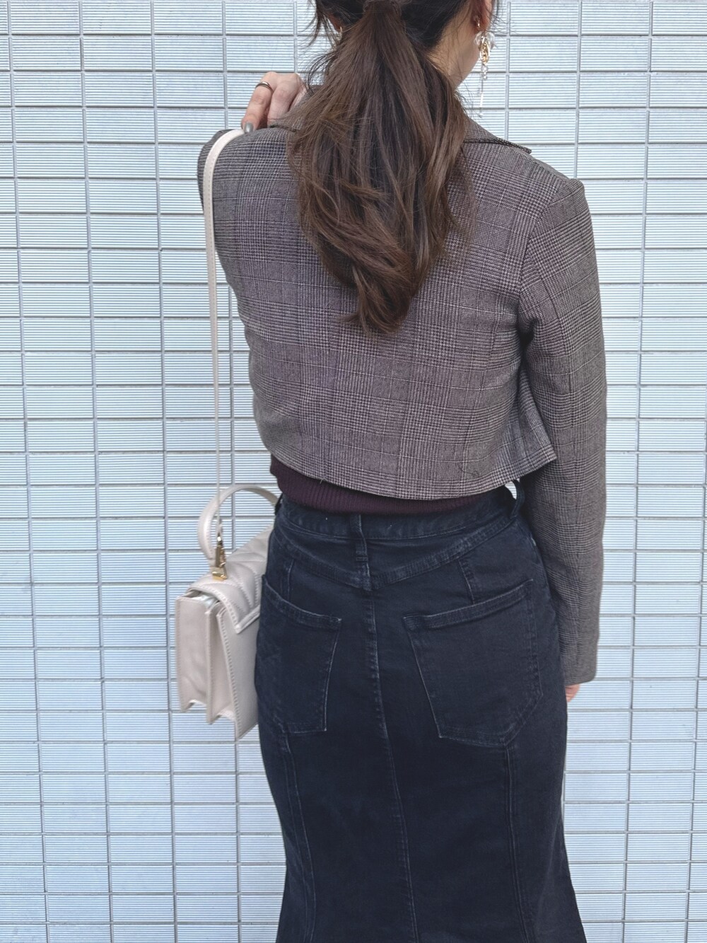 ベージュ系のショルダーバッグ、ブラック系のデニムスカート、ブラウン系のニット/セーターを着用したレディースの秋コーディネートの7枚目の写真