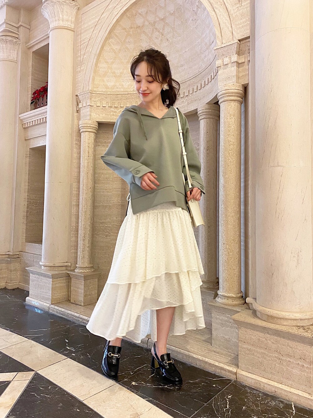 ホワイト系のスカート、ブラック系のローファー、ホワイト系のハンドバッグを着用したレディースの冬コーディネートの2枚目の写真