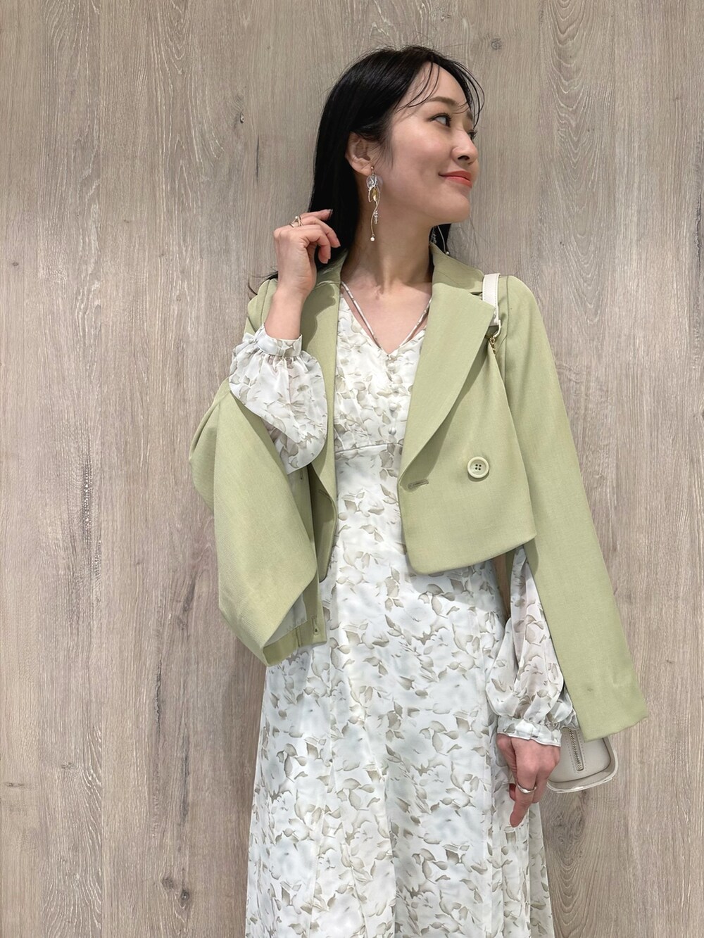 ホワイト系のハンドバッグ、ブラウン系のブーツ、グリーン系のテーラードジャケットを着用したレディースの冬コーディネートの5枚目の写真