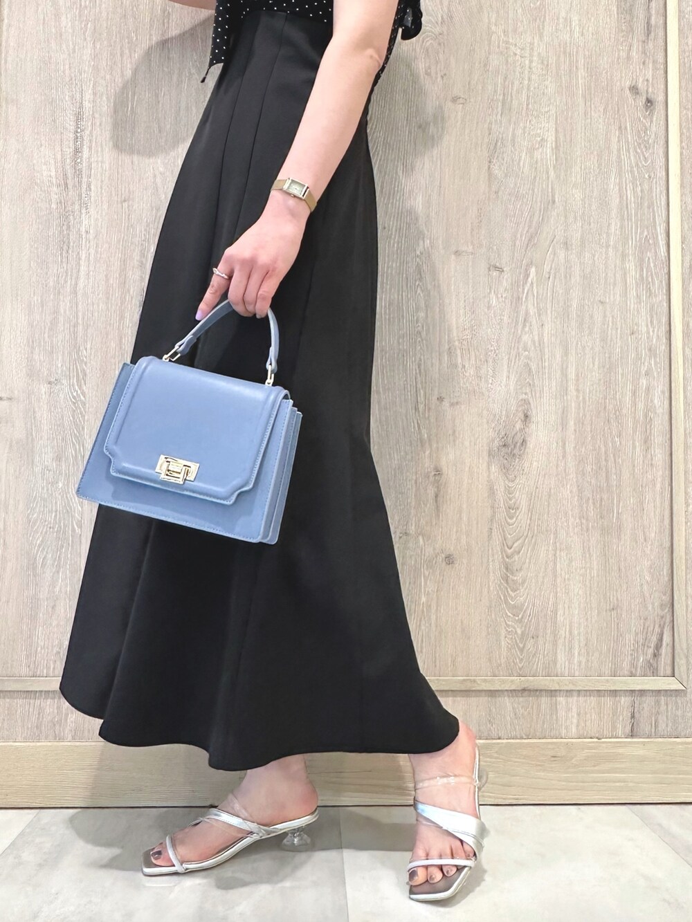 ブラック系のワンピース、ブルー系のハンドバッグ、シルバー系のサンダルを着用したレディースの春コーディネートの5枚目の写真