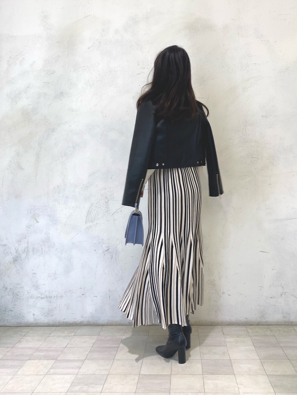 ブルー系のハンドバッグ、ブラック系のライダースジャケット、ホワイト系のワンピースを着用したレディースの冬コーディネートの3枚目の写真