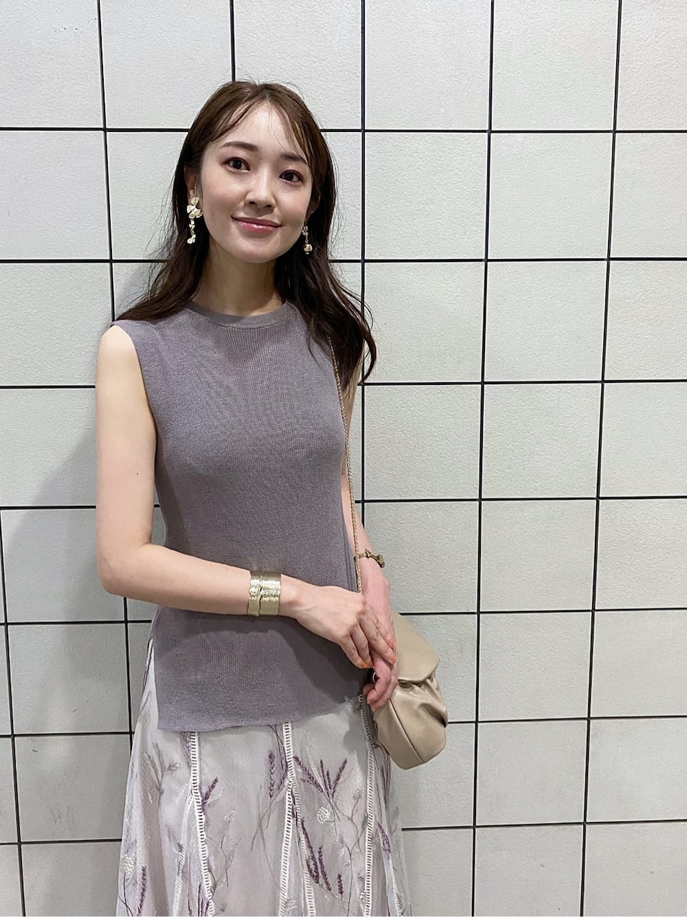 ベージュ系のクラッチバッグ、ブラウン系のサンダル、ホワイト系のスカートを着用したレディースの夏コーディネートの4枚目の写真