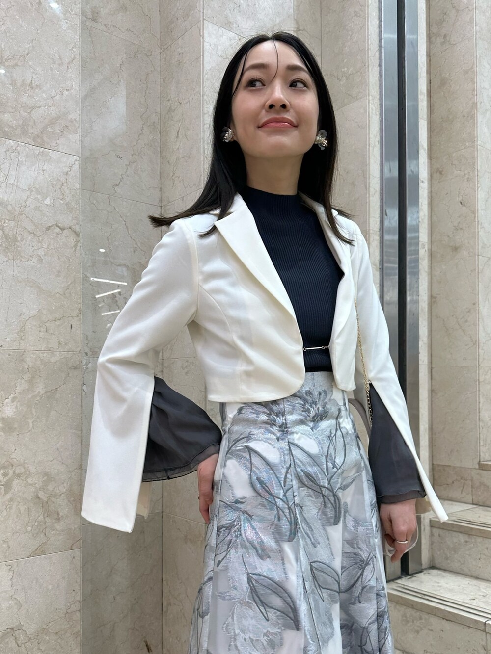 ホワイト系のテーラードジャケット、グレー系のスカート、グレー系のニット/セーターを着用したレディースの春コーディネートの4枚目の写真