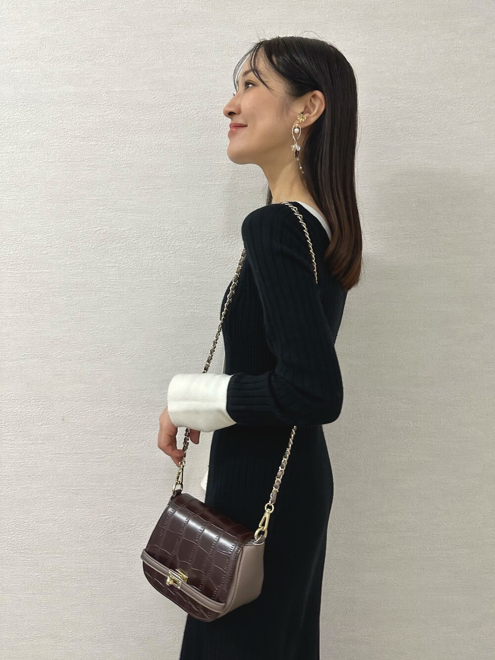 ホワイト系のブーツ、ブラウン系のハンドバッグ、ブラック系のワンピースを着用したレディースの秋コーディネートの6枚目の写真