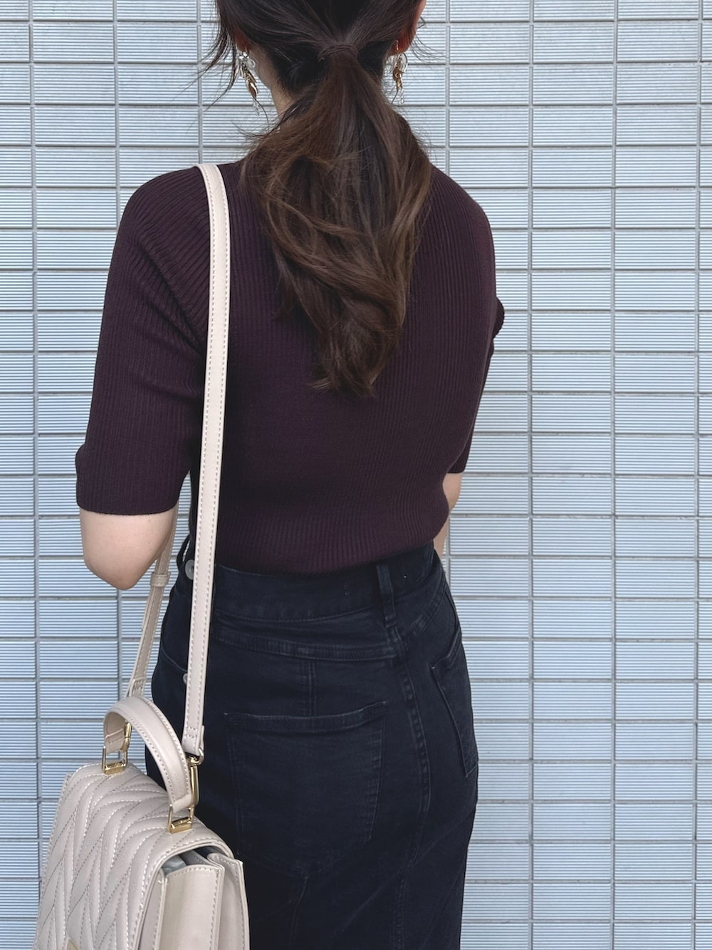 ブラウン系のニット/セーター、ブラック系のデニムスカート、ベージュ系のショルダーバッグを着用したレディースの秋コーディネートの5枚目の写真