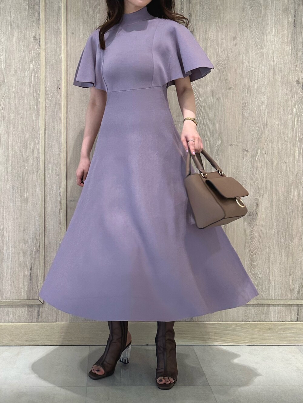 ブラウン系のハンドバッグ、ブラウン系のブーツ、パープル系のワンピースを着用したレディースの春コーディネートの2枚目の写真