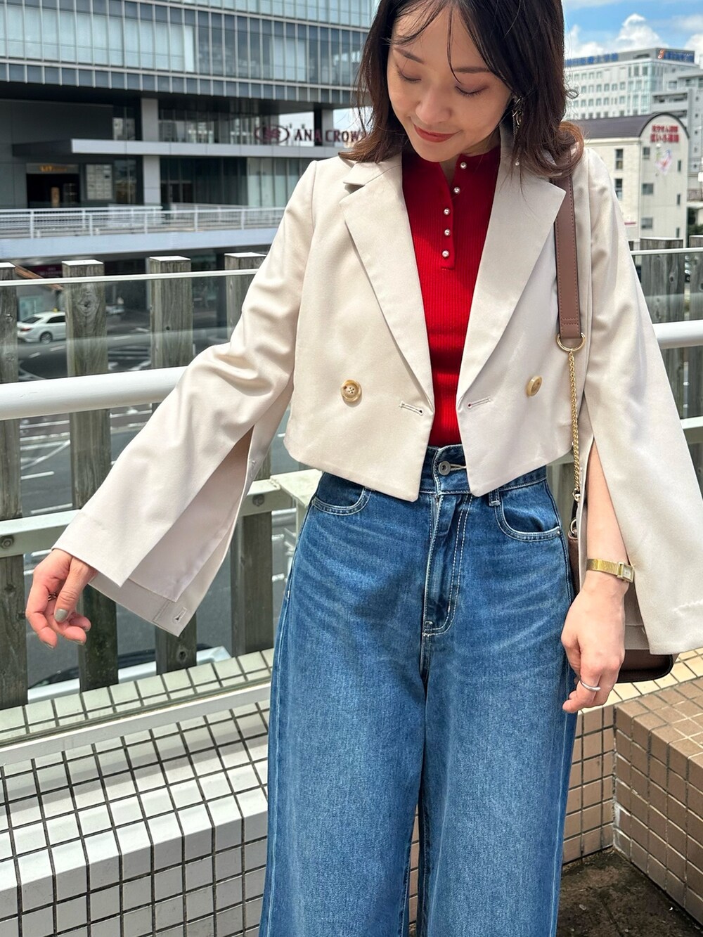 ブルー系のデニムパンツ、ブラウン系のブーツ、ブラウン系のハンドバッグを着用したレディースの夏コーディネートの6枚目の写真