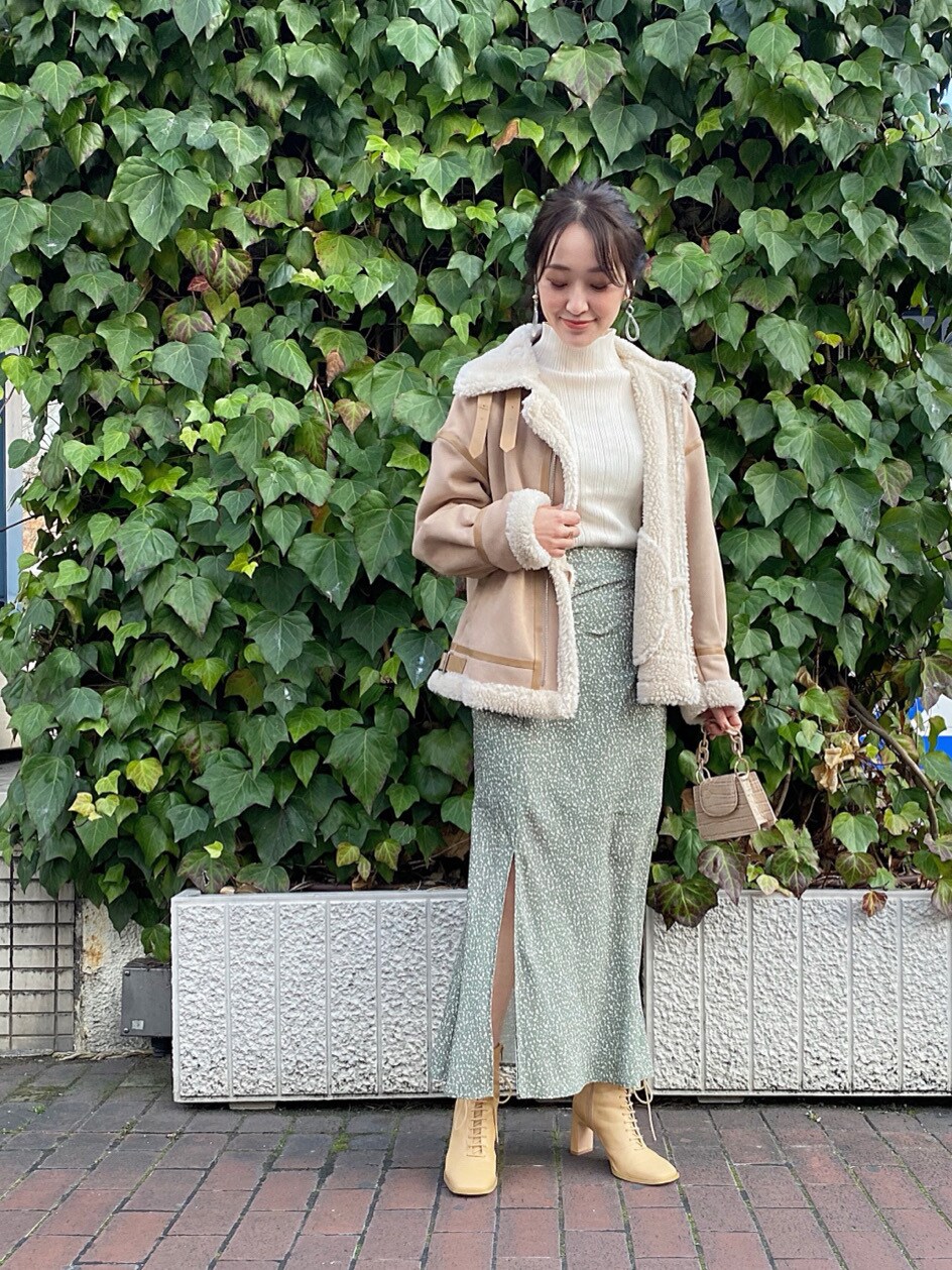 ベージュ系のムートンコート、ホワイト系のニット/セーター、ベージュ系のスカートを着用したレディースの冬コーディネートの2枚目の写真