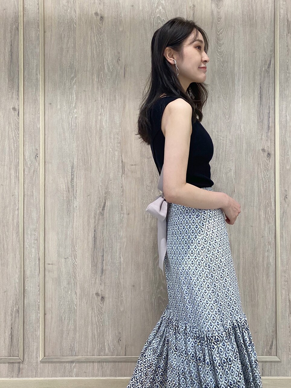 ホワイト系のハンドバッグ、ブルー系のスカート、ブラック系のニット/セーターを着用したレディースの夏コーディネートの4枚目の写真