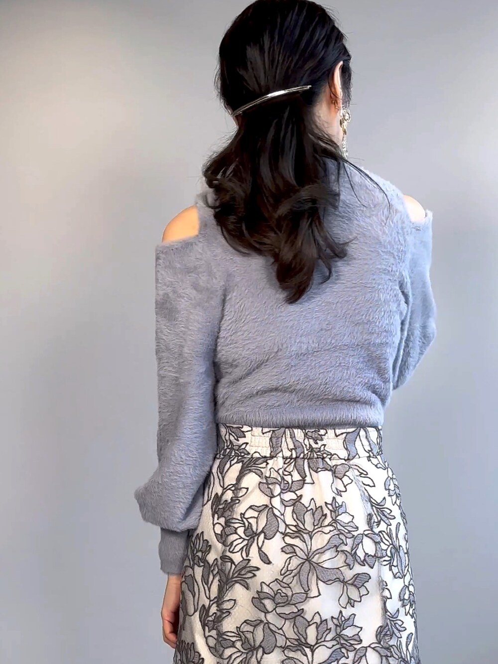 ブルー系のニット/セーター、グレー系のスカート、ブラウン系のブーツを着用したレディースの秋コーディネートの6枚目の写真