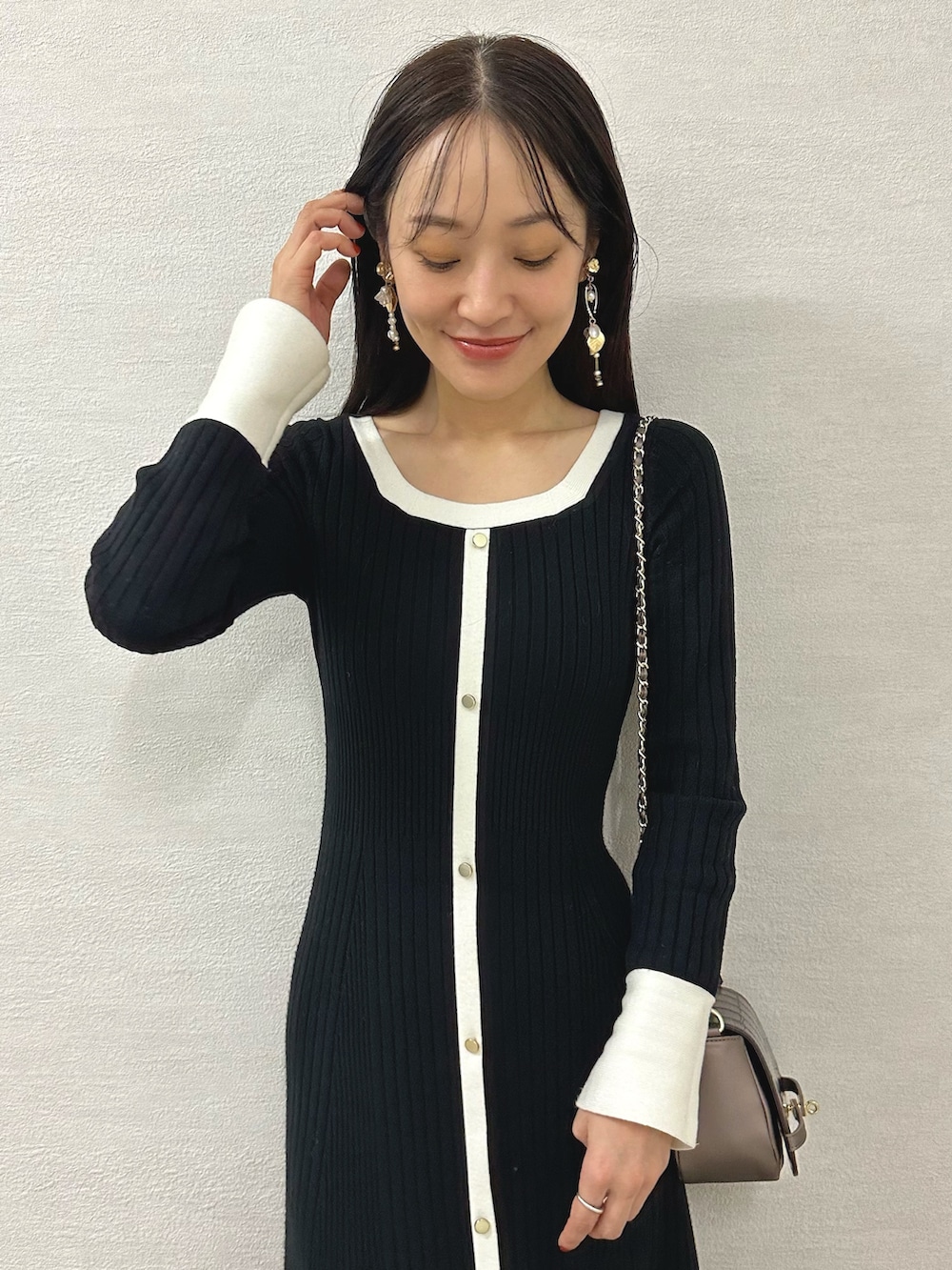 ホワイト系のブーツ、ブラウン系のハンドバッグ、ブラック系のワンピースを着用したレディースの秋コーディネートの4枚目の写真