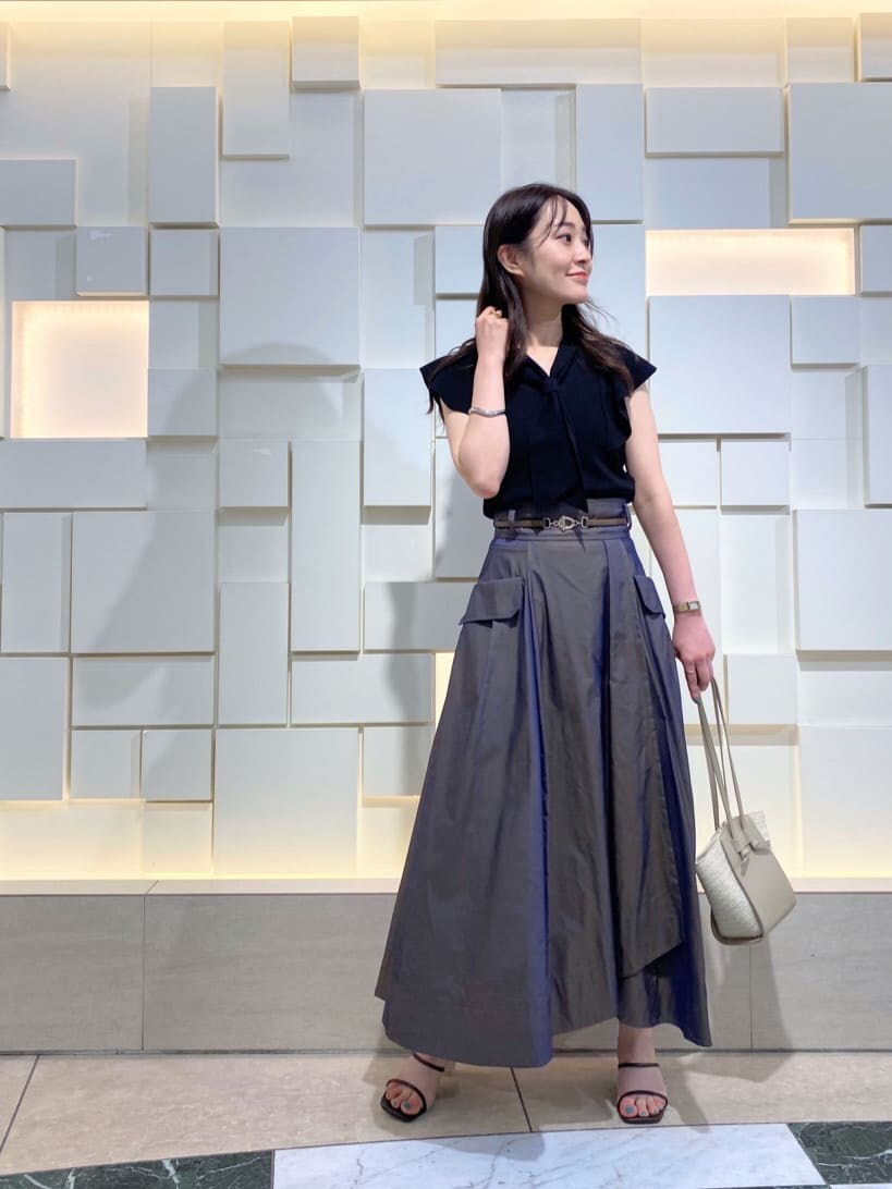 ブラック系のニット/セーター、ベージュ系のトートバッグ、ブラウン系のスカートを着用したレディースの夏コーディネートの2枚目の写真