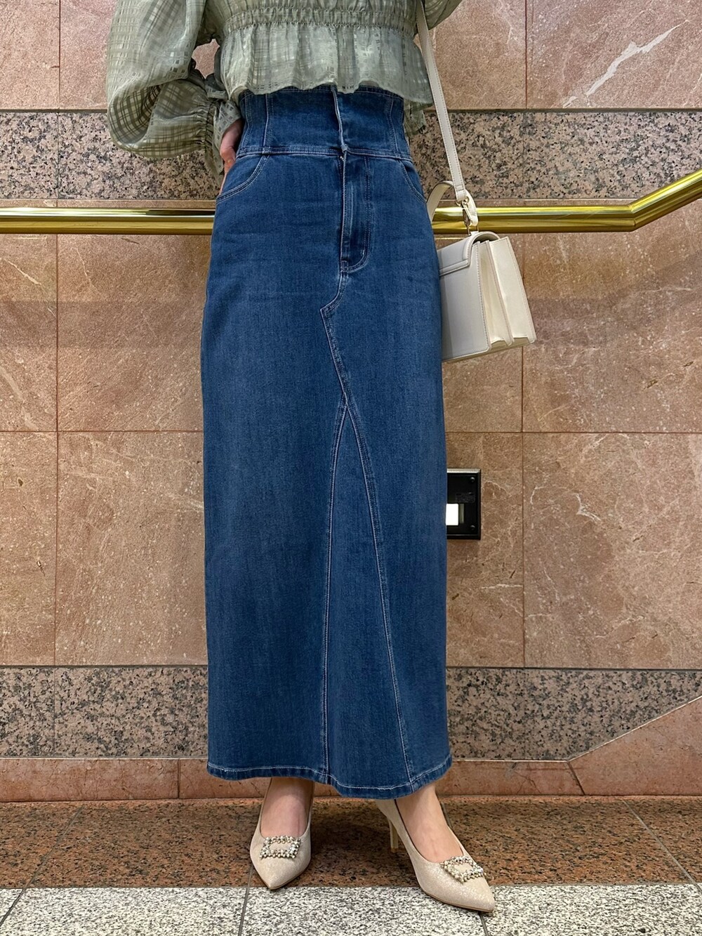 グリーン系のシャツ/ブラウス、ブルー系のデニムスカート、ベージュ系のパンプスを着用したレディースの冬コーディネートの9枚目の写真