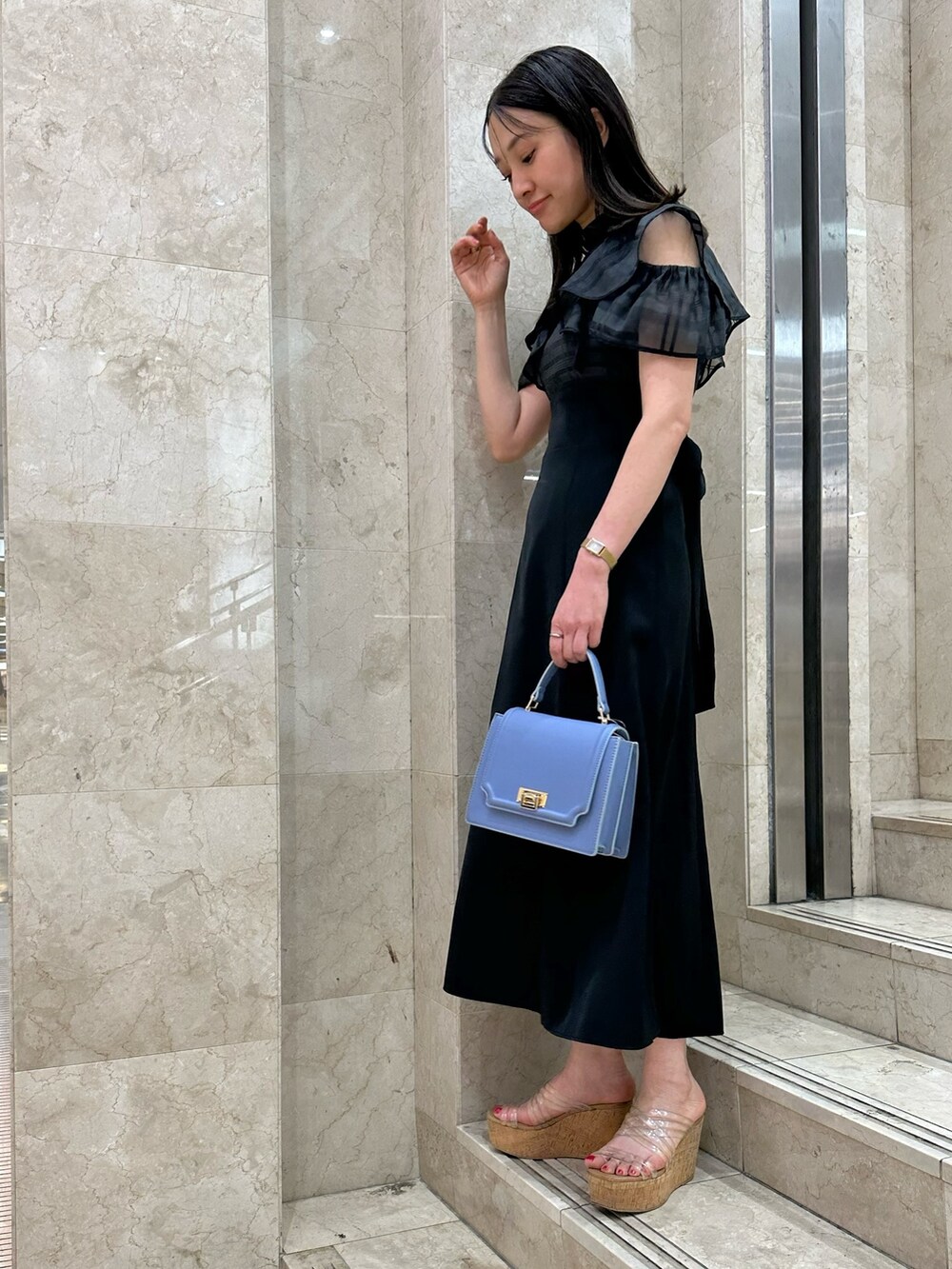ブラック系のワンピース、ブルー系のハンドバッグ、その他のサンダルを着用したレディースの春コーディネートの3枚目の写真