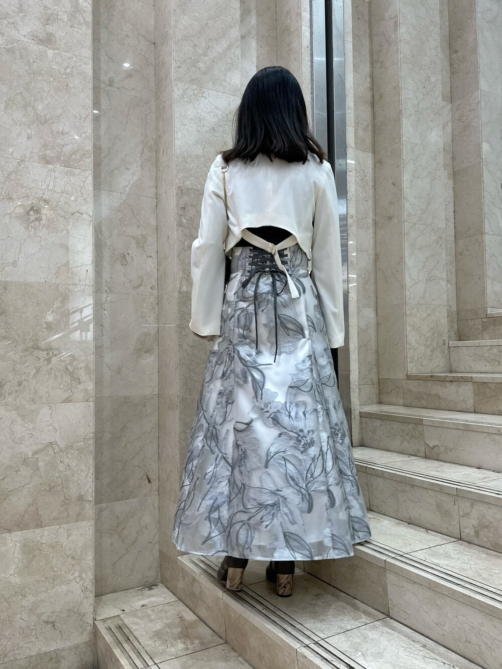 ホワイト系のテーラードジャケット、グレー系のスカート、グレー系のニット/セーターを着用したレディースの春コーディネートの3枚目の写真