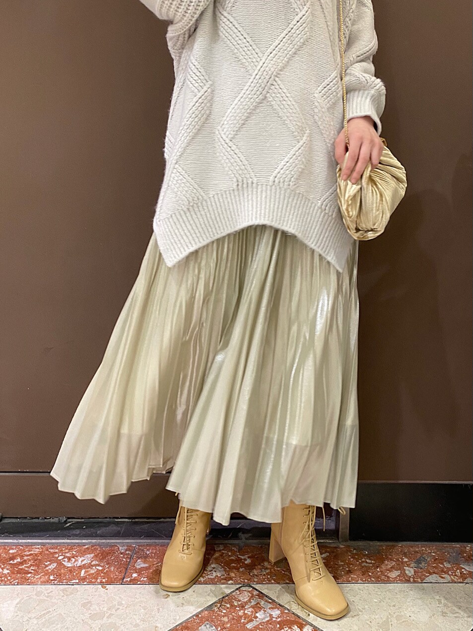 ベージュ系のクラッチバッグ、イエロー系のスカート、グレー系のニット/セーターを着用したレディースの秋コーディネートの7枚目の写真