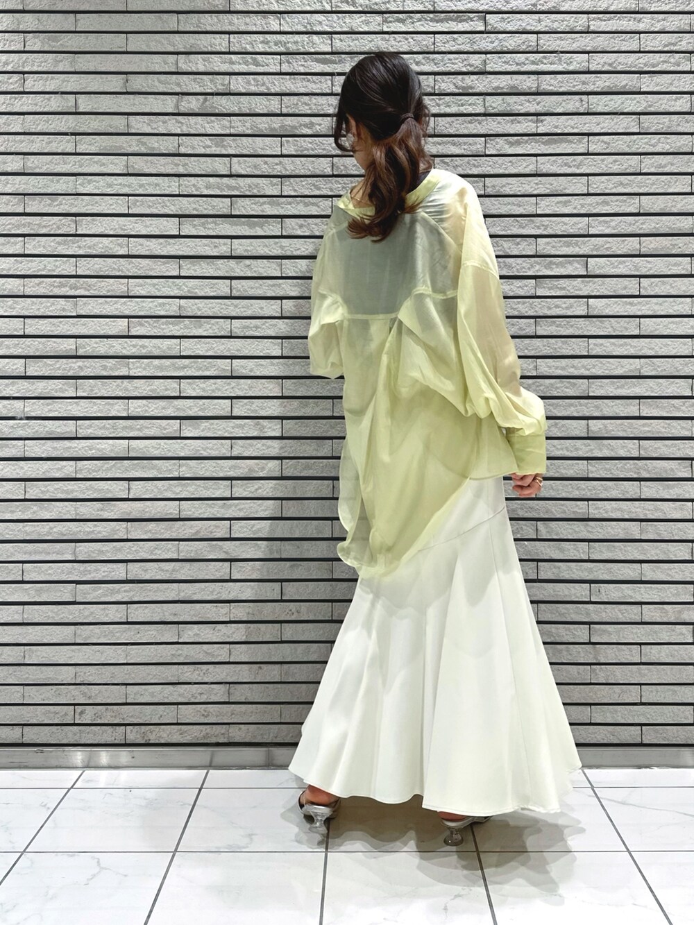 シルバー系のサンダル、ホワイト系のスカート、グレー系のニット/セーターを着用したレディースの春コーディネートの4枚目の写真