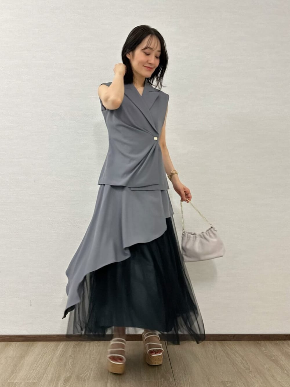 ブラック系のチューブトップ、ピンク系のショルダーバッグ、グレー系のベストを着用したレディースの春コーディネートの2枚目の写真