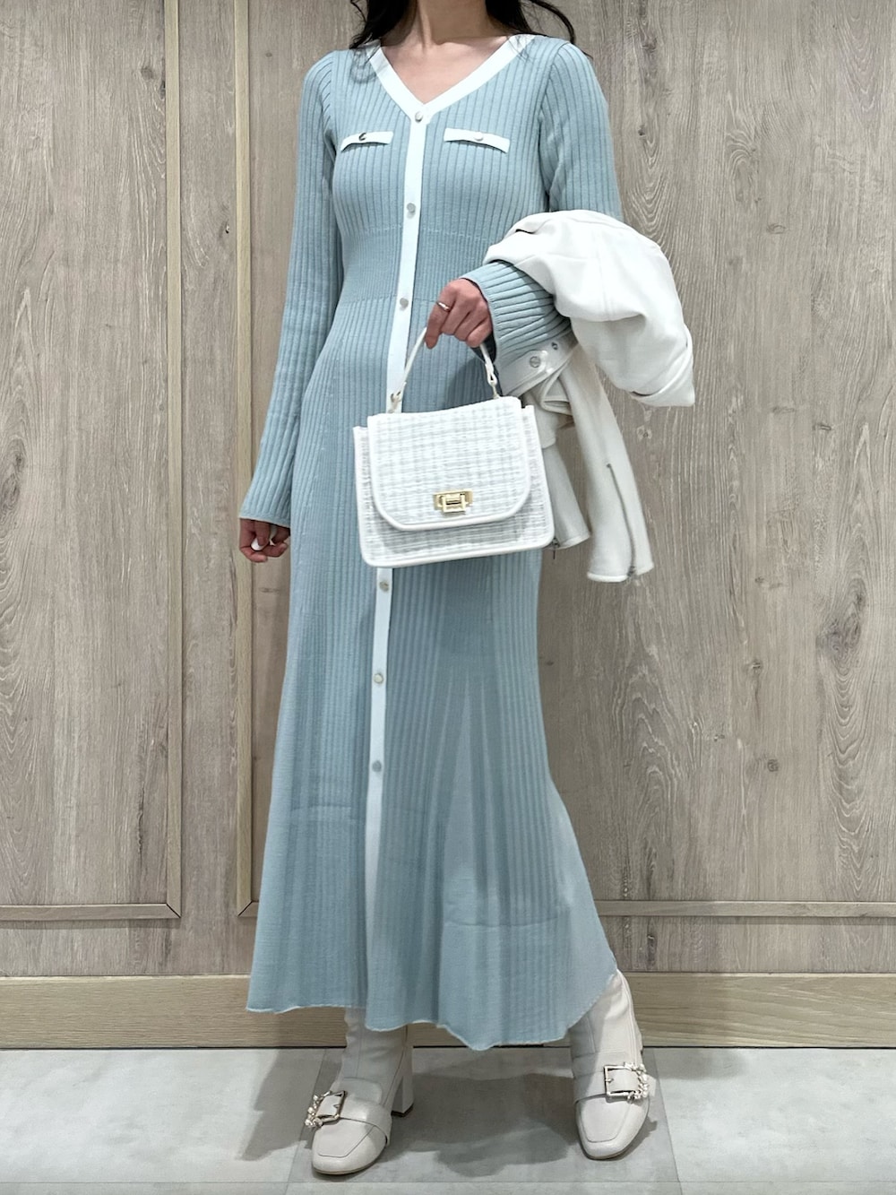 ホワイト系のハンドバッグ、ホワイト系のブーツ、ブルー系のワンピースを着用したレディースの冬コーディネートの3枚目の写真