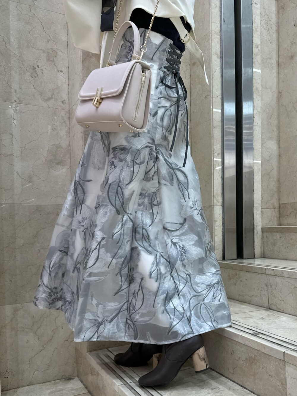 ホワイト系のテーラードジャケット、グレー系のスカート、グレー系のニット/セーターを着用したレディースの春コーディネートの8枚目の写真