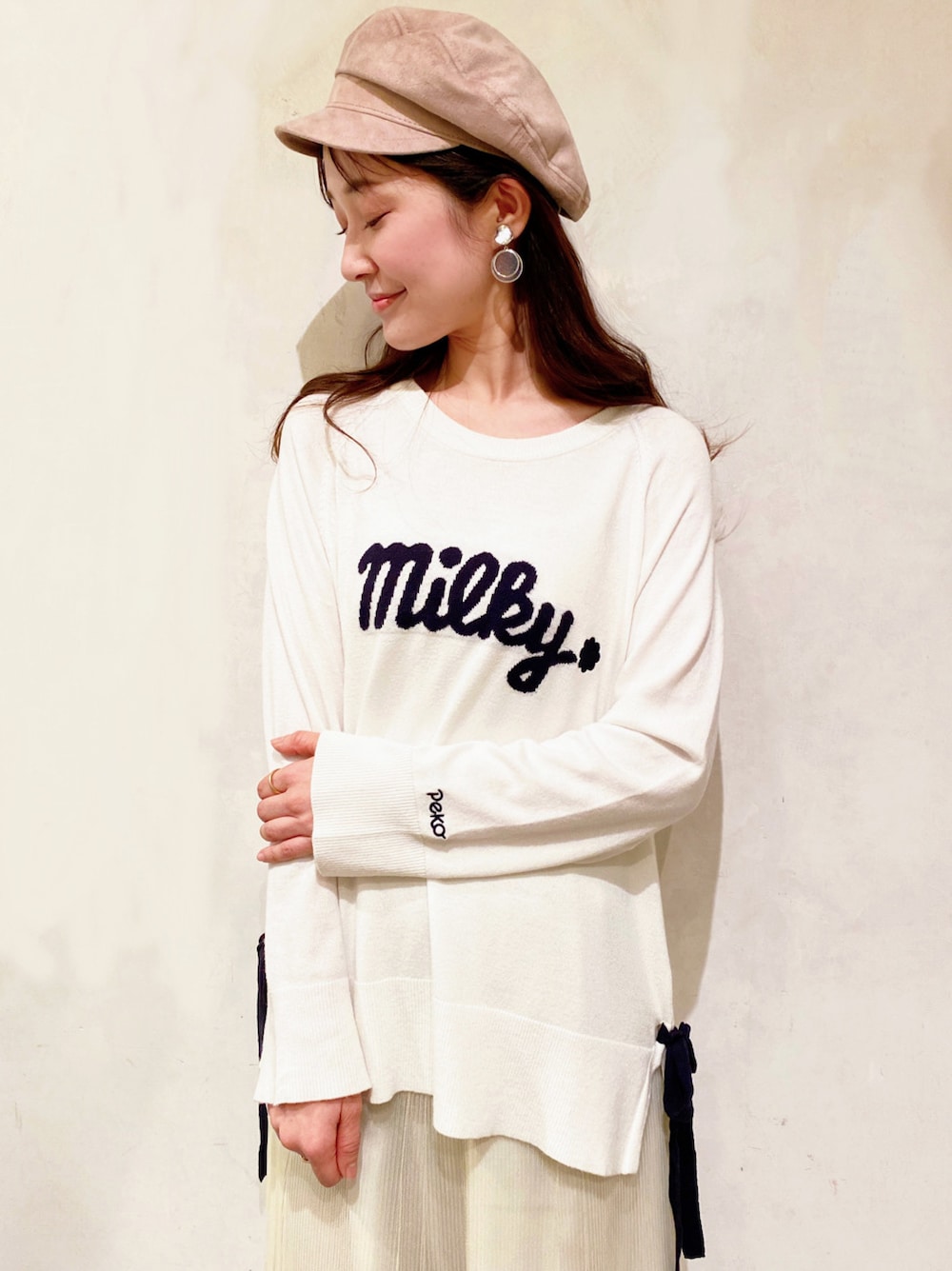 イエロー系のスカート、ベージュ系のパンプス、ホワイト系のニット/セーターを着用したレディースの冬コーディネートの3枚目の写真