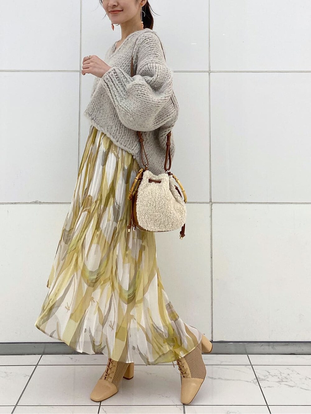 イエロー系のスカート、グレー系のニット/セーター、ベージュ系のブーツを着用したレディースの秋コーディネートの3枚目の写真
