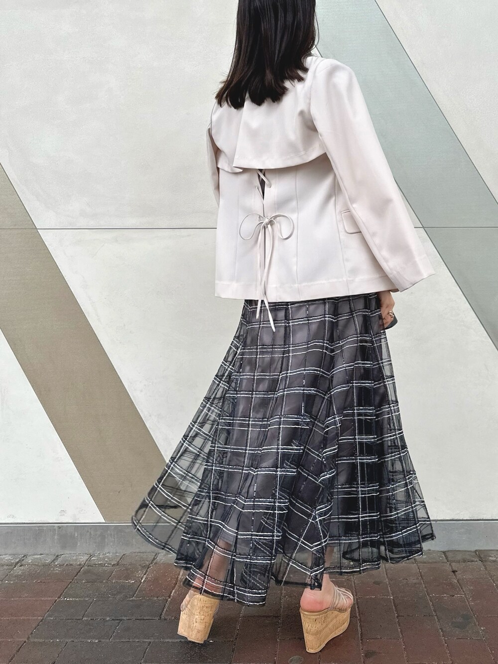 ブラック系のハンドバッグ、ブラック系のスカート、その他のサンダルを着用したレディースの春コーディネートの4枚目の写真