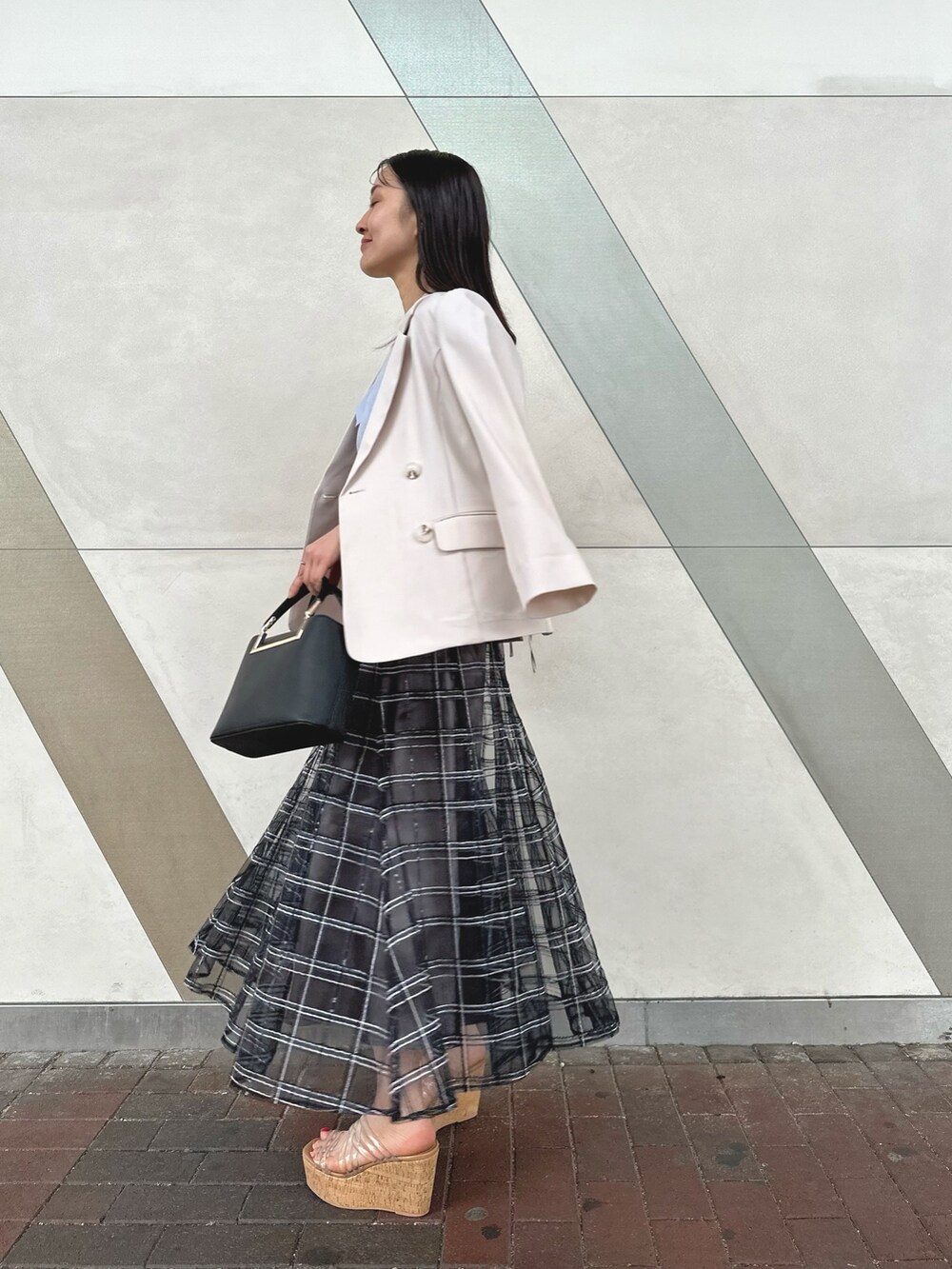 ブラック系のハンドバッグ、ブラック系のスカート、その他のサンダルを着用したレディースの春コーディネートの3枚目の写真