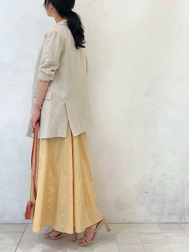 イエロー系のワンピース、ベージュ系のニット/セーター、ホワイト系のテーラードジャケットを着用したレディースの春コーディネートの5枚目の写真