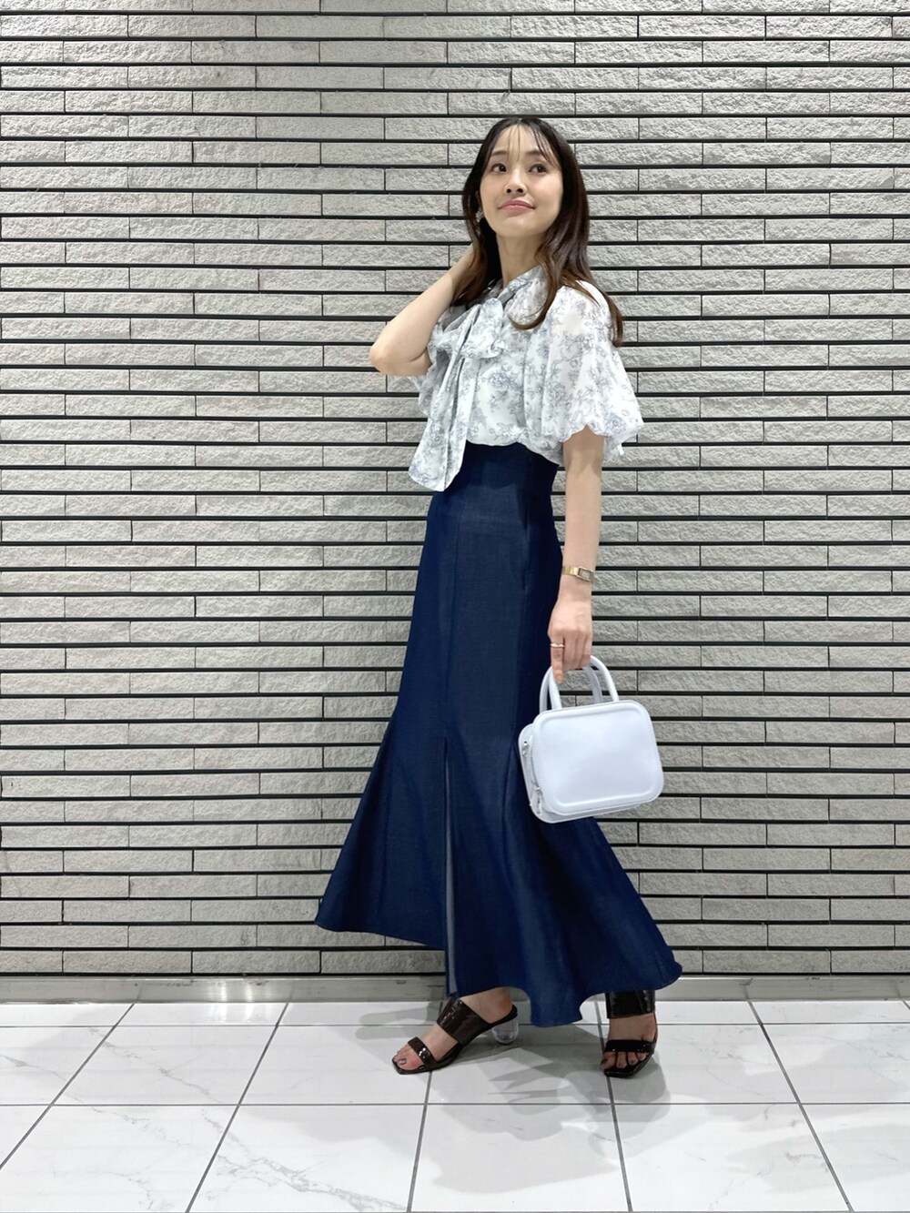 ブルー系のハンドバッグ、ブルー系のスカート、ブルー系のシャツ/ブラウスを着用したレディースの夏コーディネートの2枚目の写真