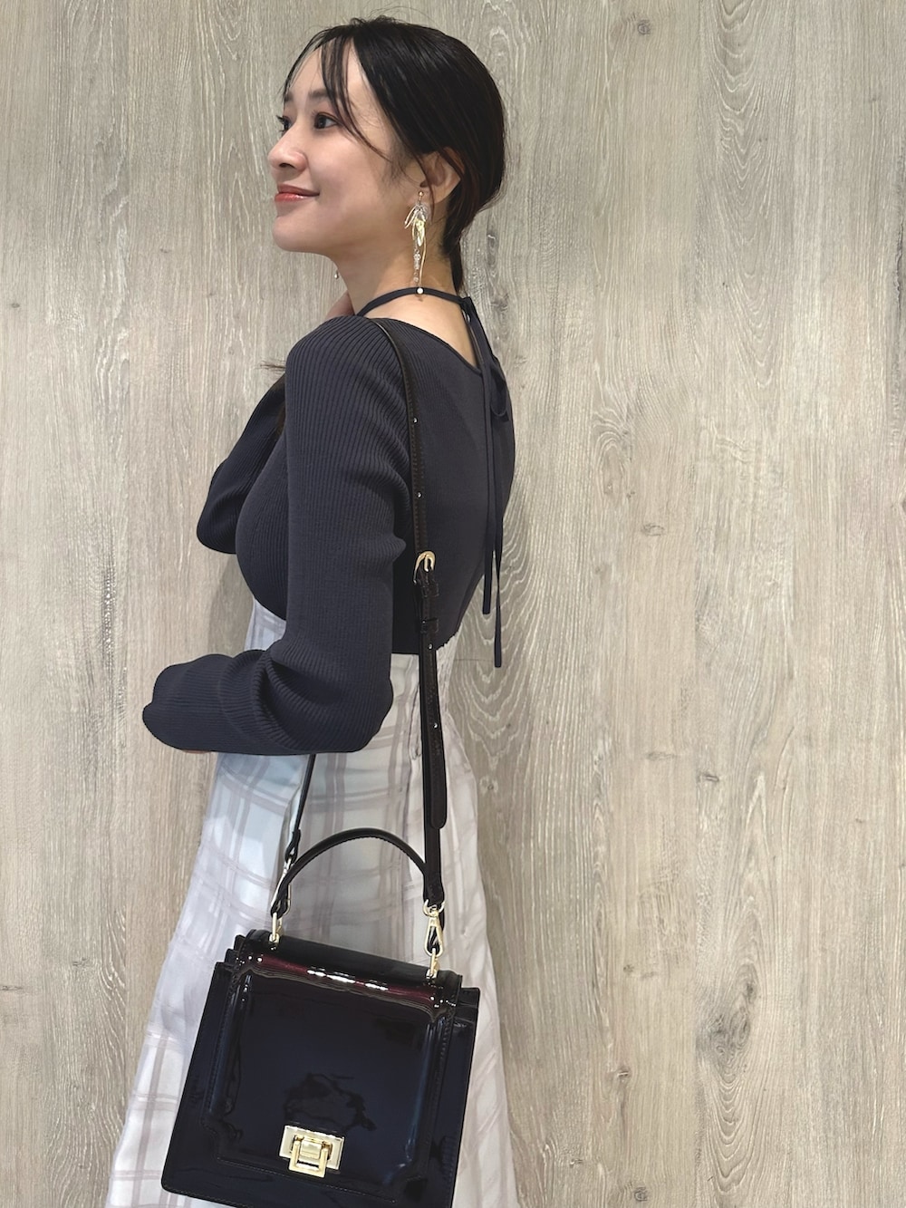 レッド系のハンドバッグ、ブラウン系のパンプス、グレー系のワンピースを着用したレディースの秋コーディネートの7枚目の写真