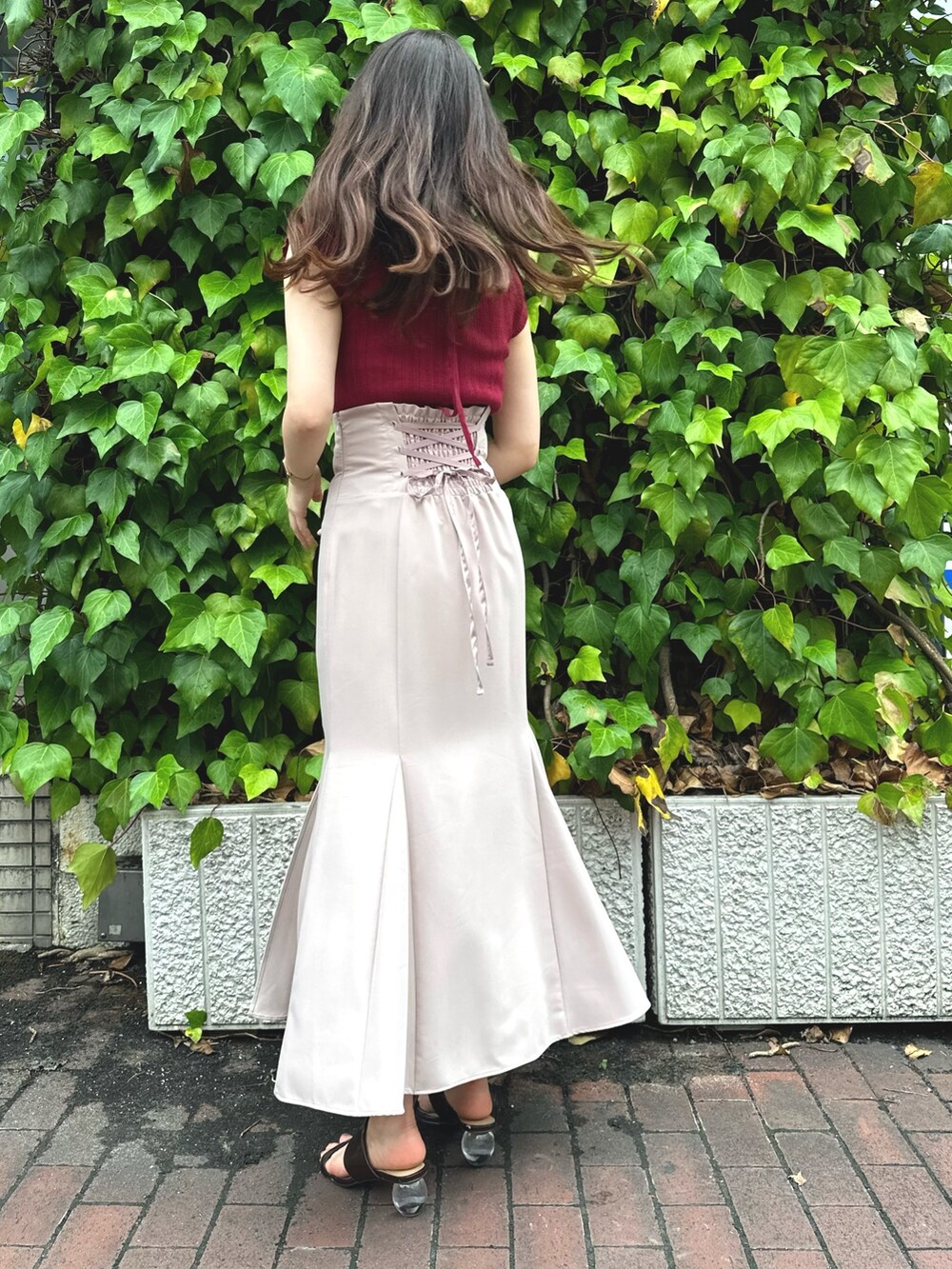 ブラウン系のサンダル、レッド系のニット/セーター、ピンク系のスカートを着用したレディースの夏コーディネートの3枚目の写真