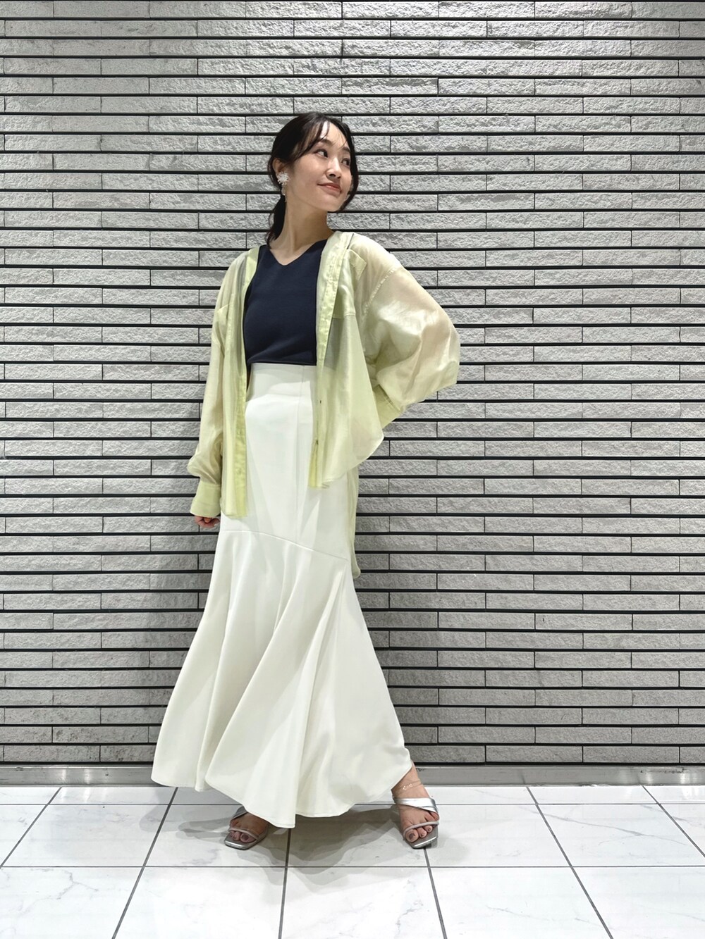 シルバー系のサンダル、ホワイト系のスカート、グレー系のニット/セーターを着用したレディースの春コーディネートの2枚目の写真