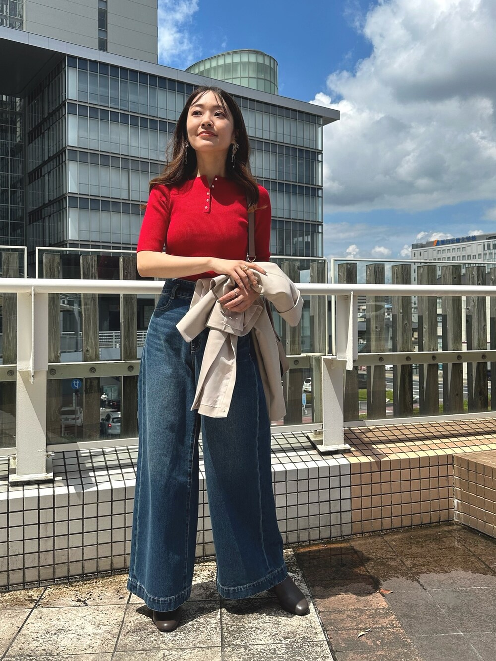 レッド系のニット/セーター、ブルー系のデニムパンツ、ブラウン系のブーツを着用したレディースの夏コーディネートの2枚目の写真