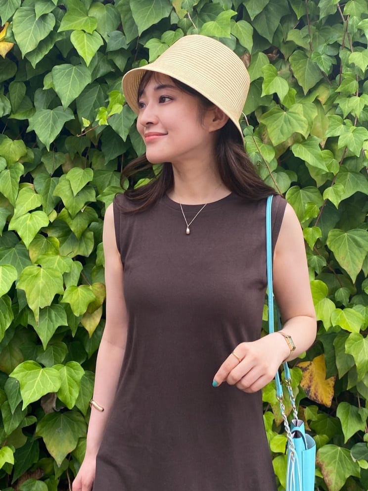 グリーン系のショルダーバッグ、ブラウン系のサンダル、ベージュ系のキャミソールを着用したレディースの夏コーディネートの2枚目の写真