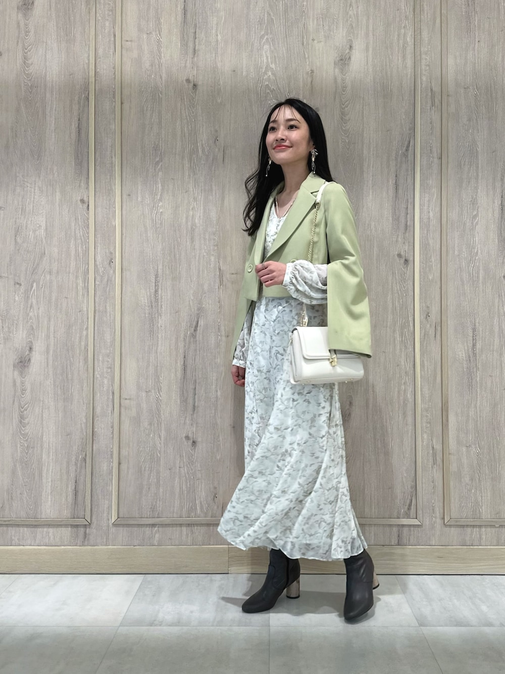 ホワイト系のハンドバッグ、ブラウン系のブーツ、グリーン系のテーラードジャケットを着用したレディースの冬コーディネートの2枚目の写真