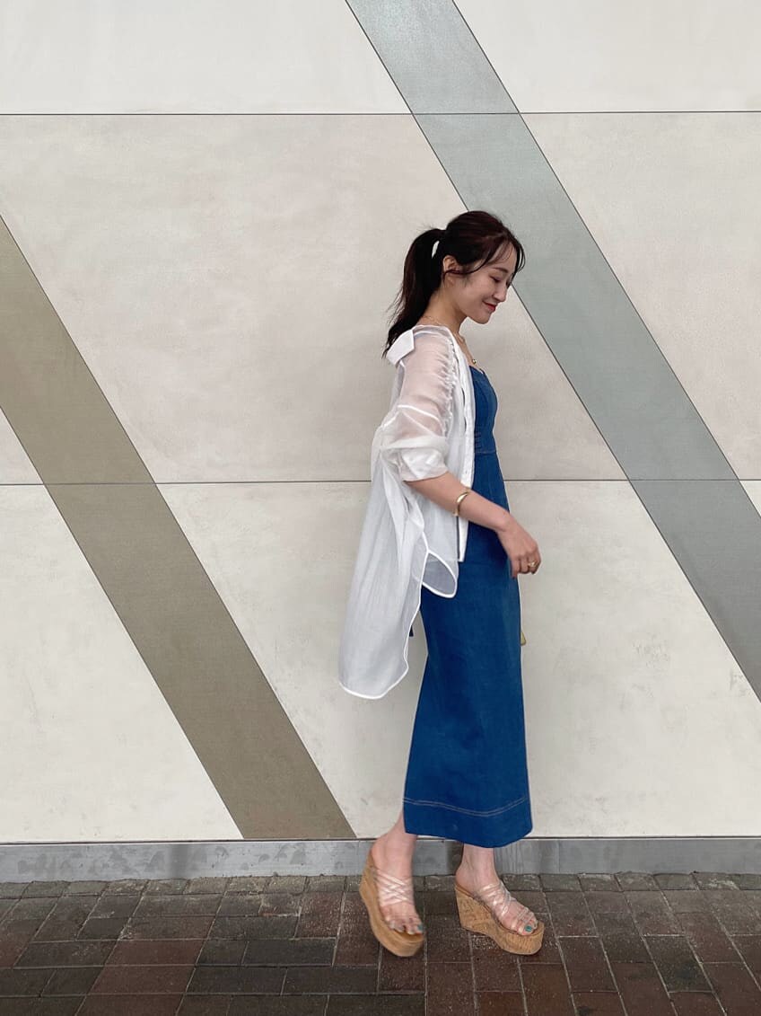 イエロー系のショルダーバッグ、ブルー系のジャンパースカート、ベージュ系のキャミソールを着用したレディースの春コーディネートの3枚目の写真