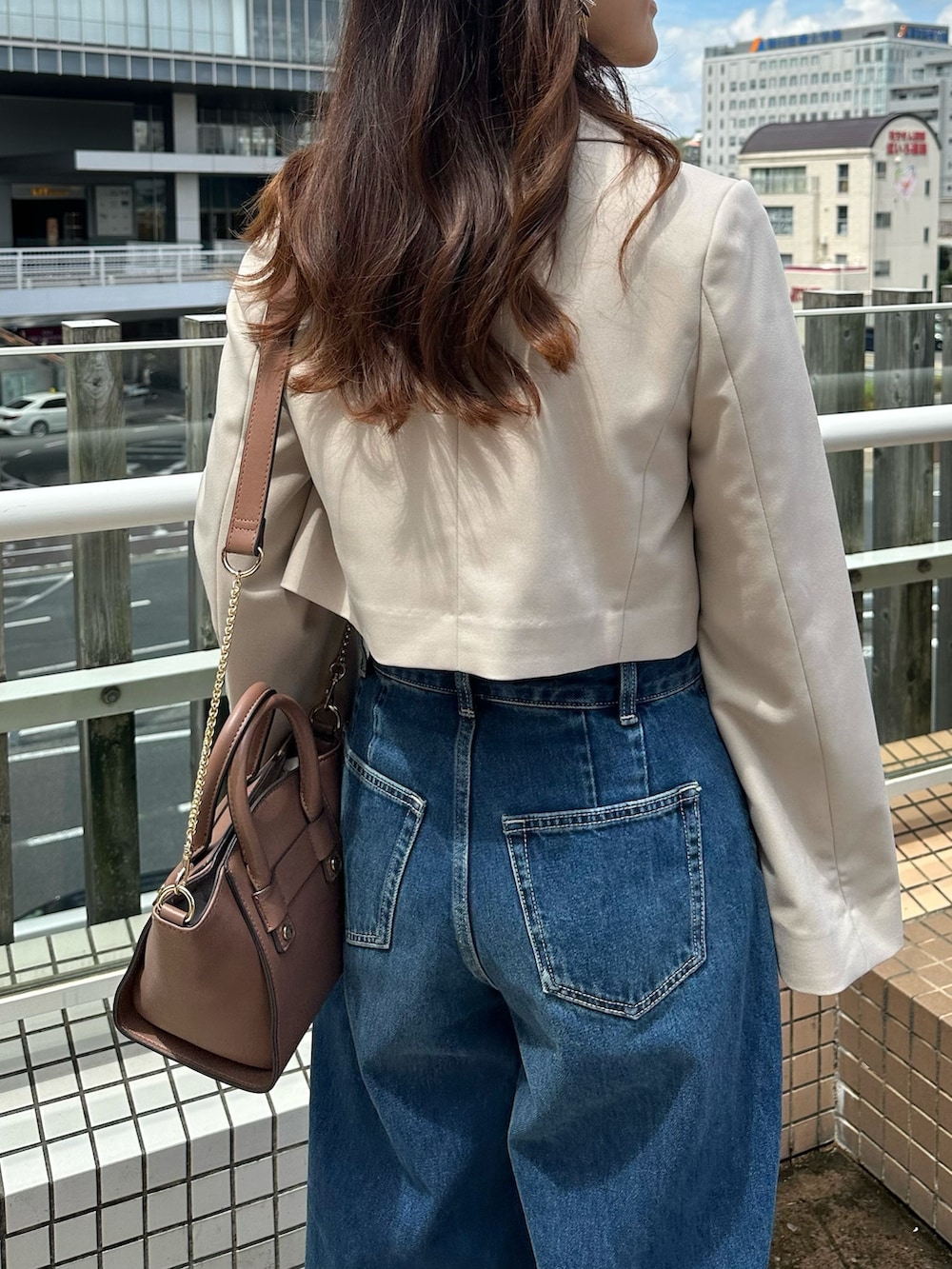 ブルー系のデニムパンツ、ブラウン系のブーツ、ブラウン系のハンドバッグを着用したレディースの夏コーディネートの7枚目の写真